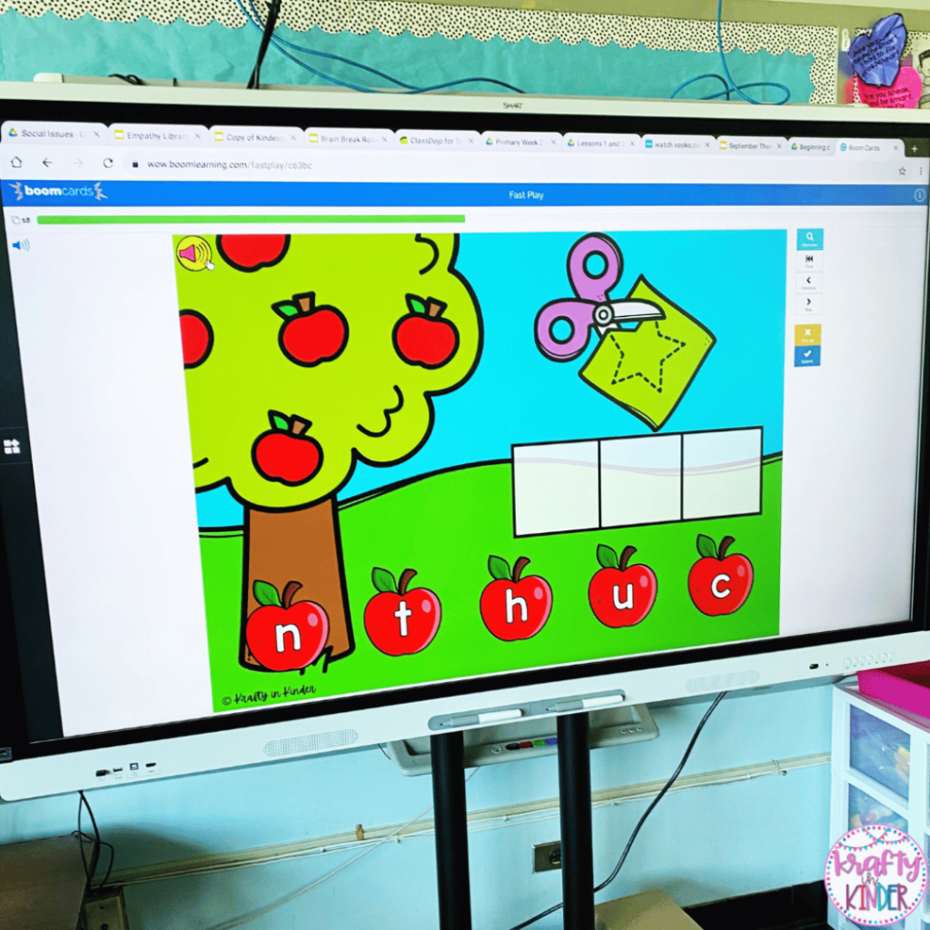 This photo showcases a digital spelling game that is being played on a classroom smart board. Students will build cvc words using moveable letters on the screen.